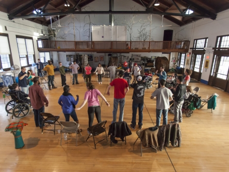 Group of young adults with various disabilities standing in a circle in a gym