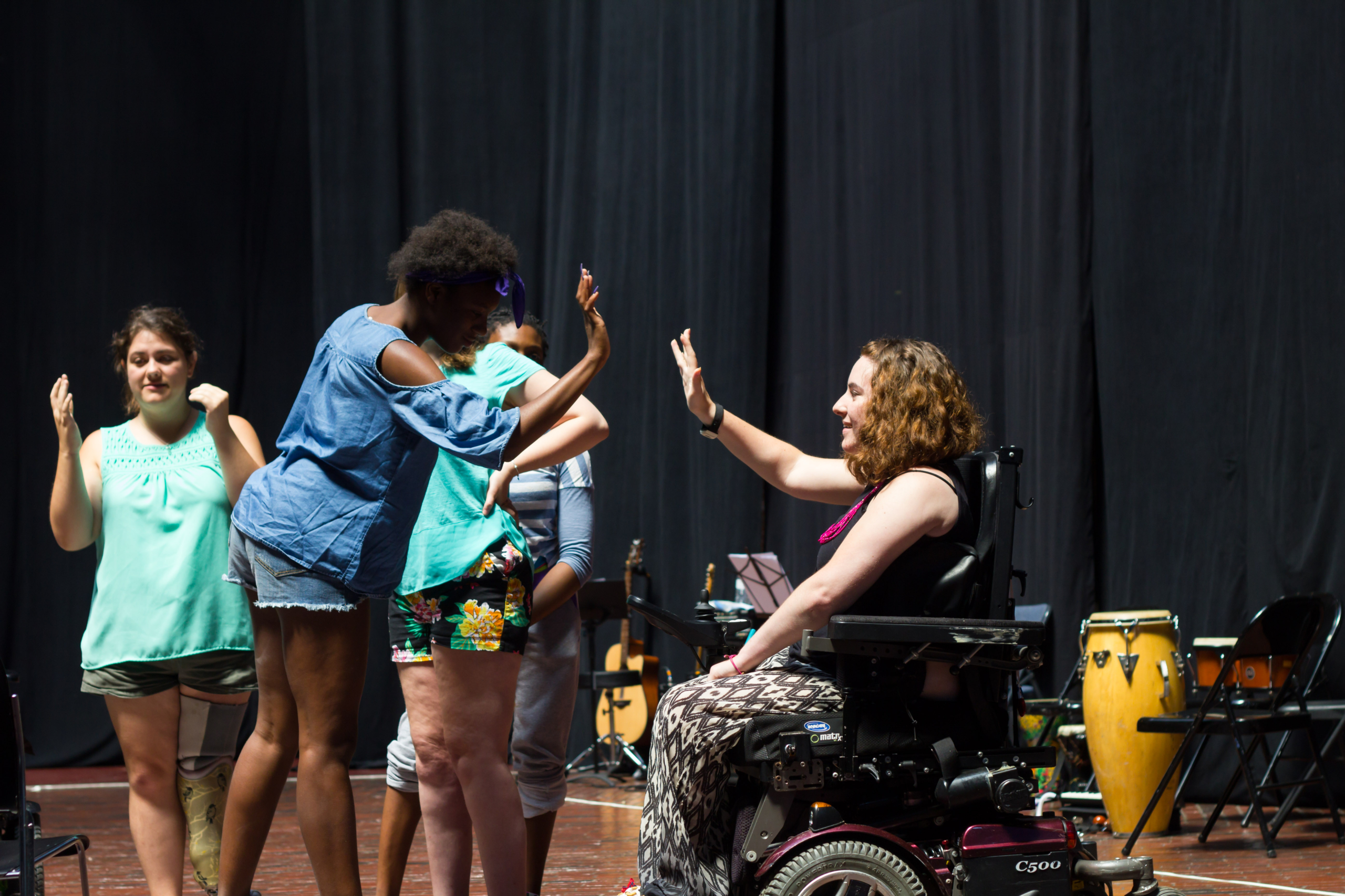 A young black woman and a young white woman in a wheelchair giving each other a high five