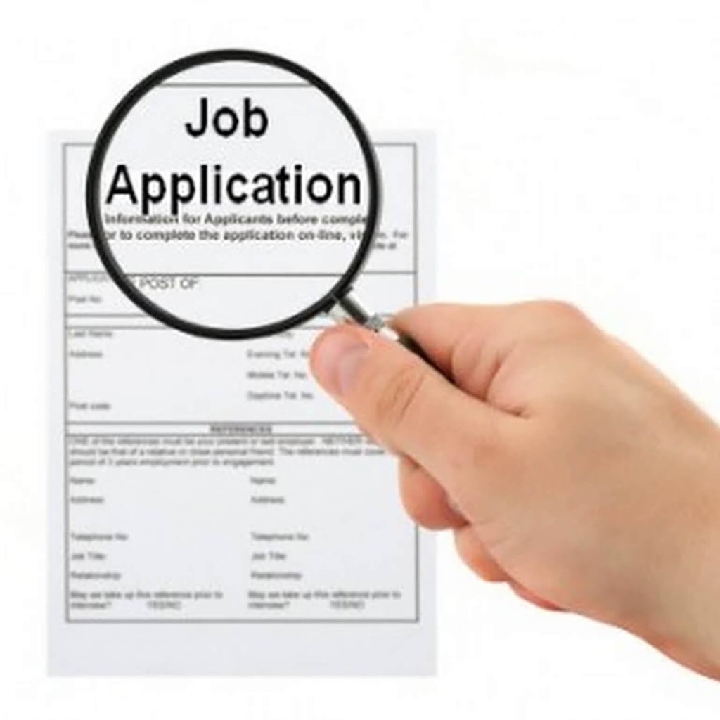 Image of a paper job application with a hand hovering over the title “Job Application” with a magnifying glass.
