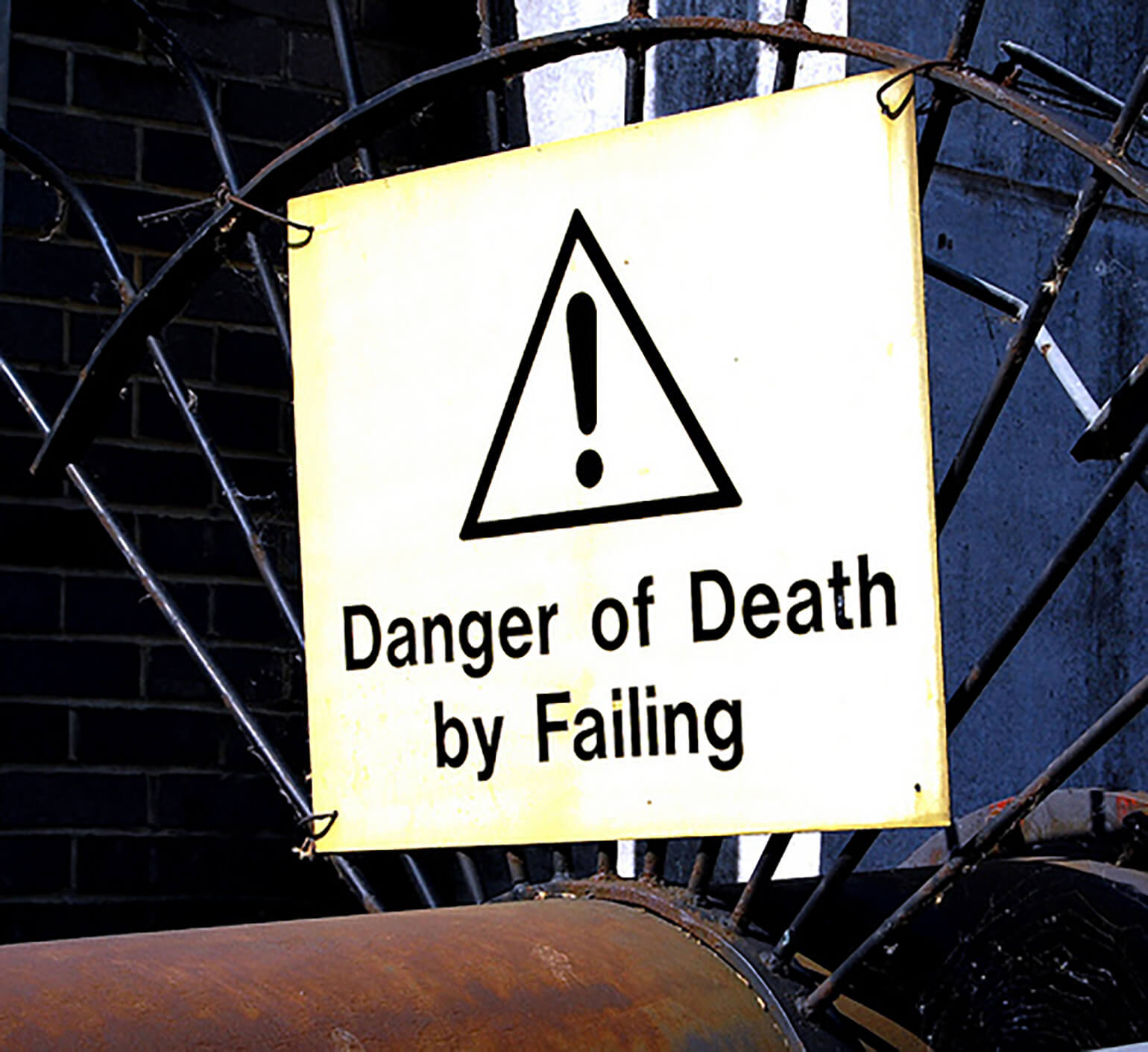 This is an image of a washed-out yellow sign that states 'danger of death by failing'. Very likely, you will not die if you make a mistake as an entrepreneur. This sign can serve to put mistakes into perspective. It is also a mistake in and of itself.