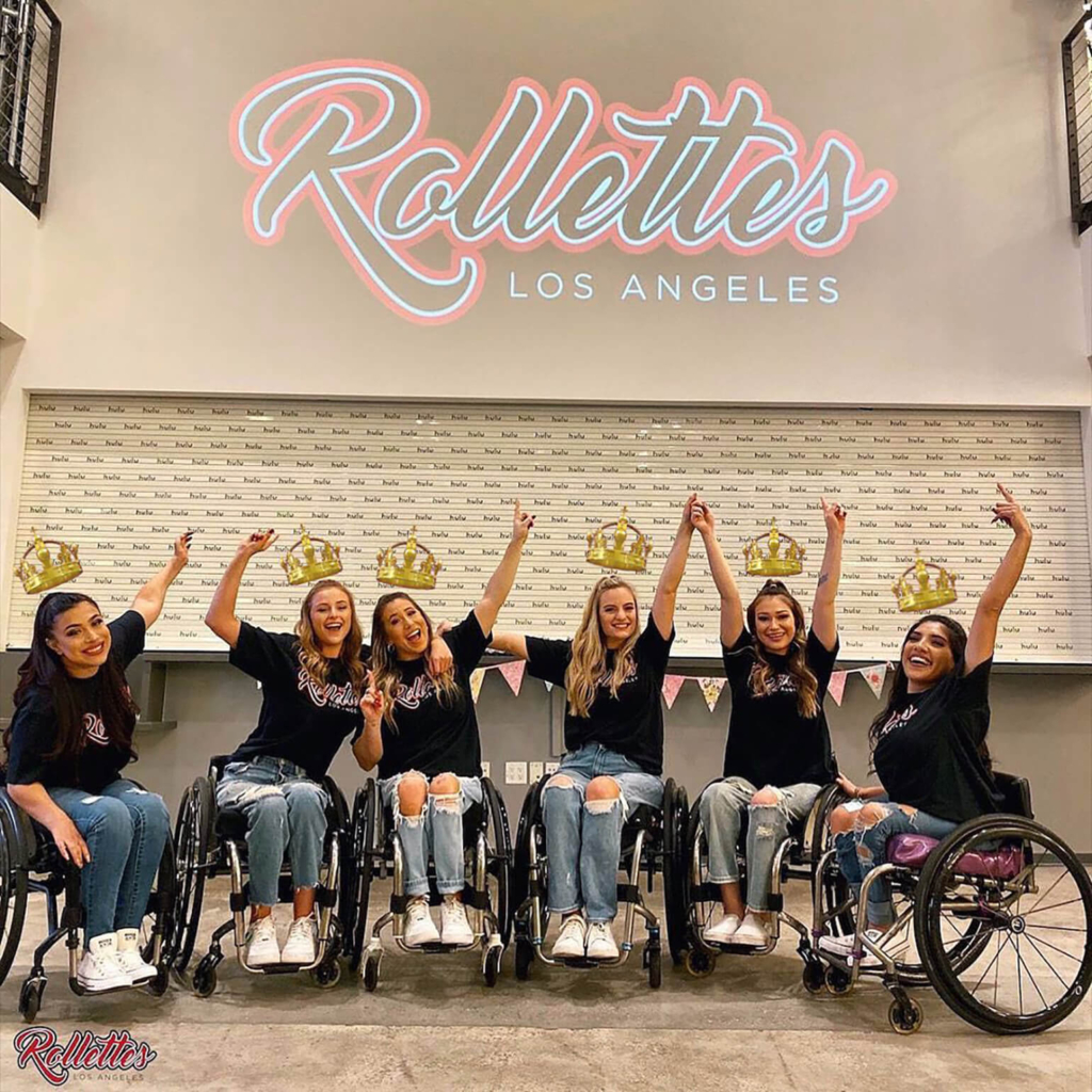 Picture is of six members of the L.A. Rollettes. All young women with raised arms in wheelchairs, wearing black teeshirts, jeans, and white sneakers. Photo credit: Forbes, October 7, 2020.