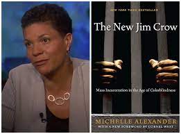 On the left in front of a blue background a Black woman with a short pixie haircut, tan sweater, black blouse and silver necklace is seated. She is author Michelle Alexander to the right is the cover of her book which is black with two Black hands holding prison bars. Her book is 'The New Jim Crow'.