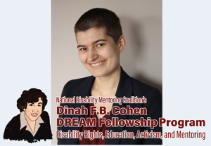 A fair-skinned androgynous person with a dark brown buzz cut and brown eyes smiles at the camera. They are standing in front of a light gray wall. They are wearing a dark red shirt and a navy blue blazer overtop.